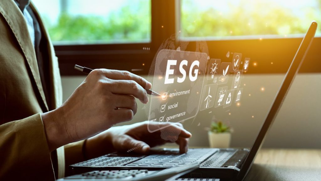 Profissional utiliza notebook com interface digital destacando critérios ESG: ambiente, social e governança.